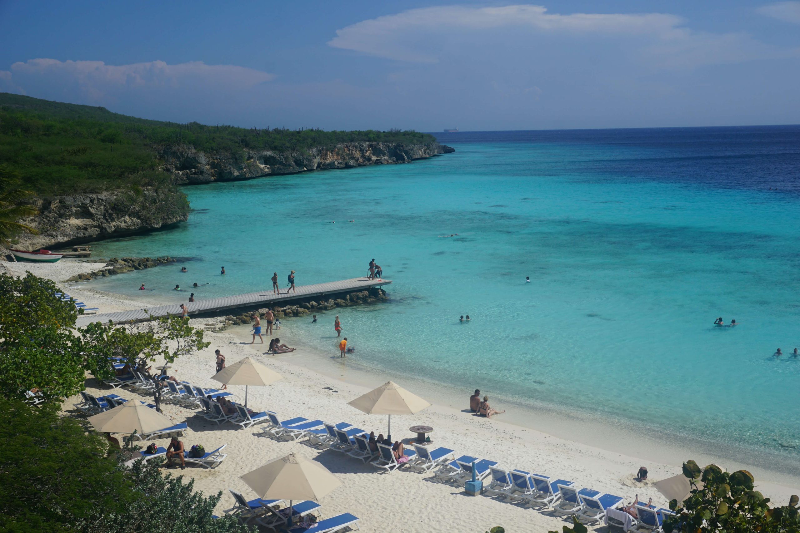 playa porto mari beach with light blue waters. people lay in the water and on the beach